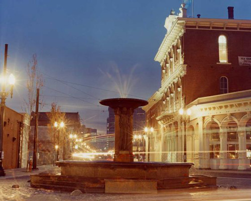 One of the oldest fountains in Portland with the lights of the Max lightrail train passing by.