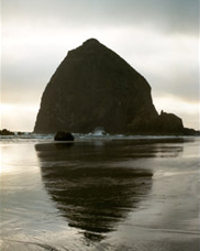 Mid summer evening view of Haystack Rock,  the Needles and beachcombers at Cannon Beach; location for the film: The Goonies